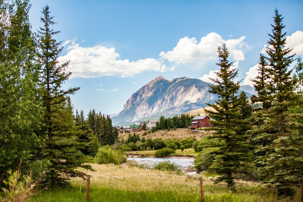 a scenic view of a mountain with a river in the foreground, Crested Butte, Colorado, places to see