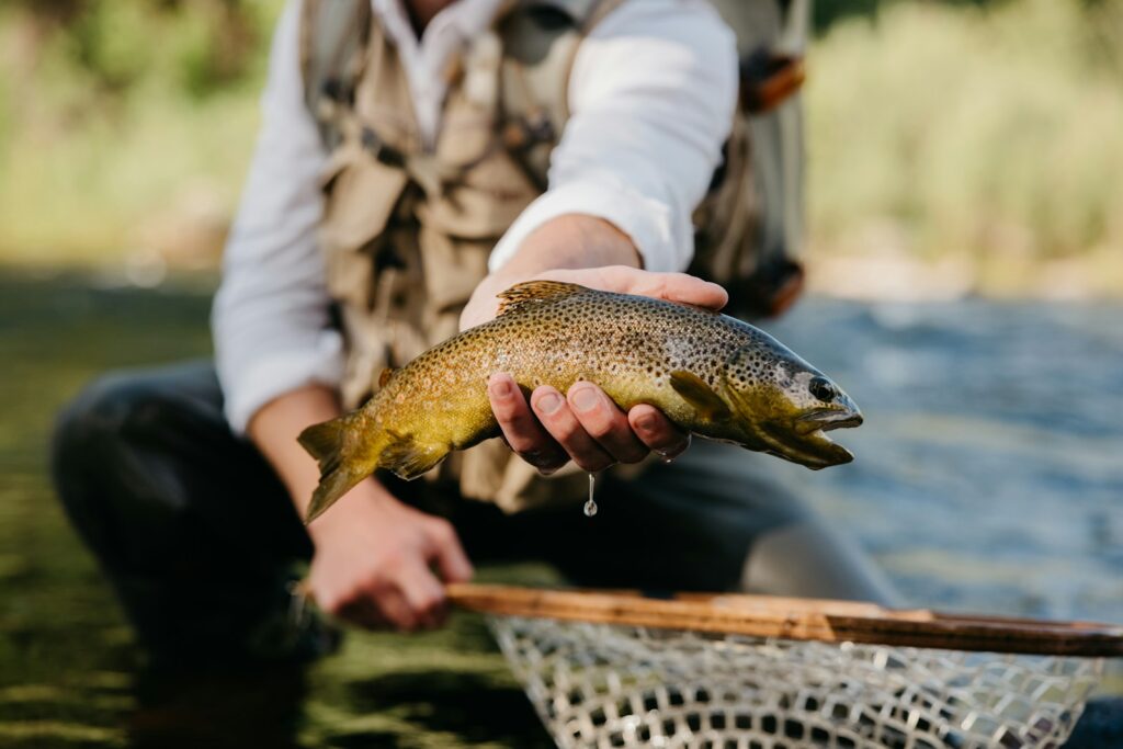 Photo by Matthew McBrayer - Colorado Frontiers a man holding a brown fish in a net